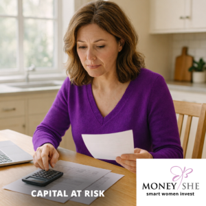women in a purple jumper sitting at her desk looking at her finances with a calculator and paper