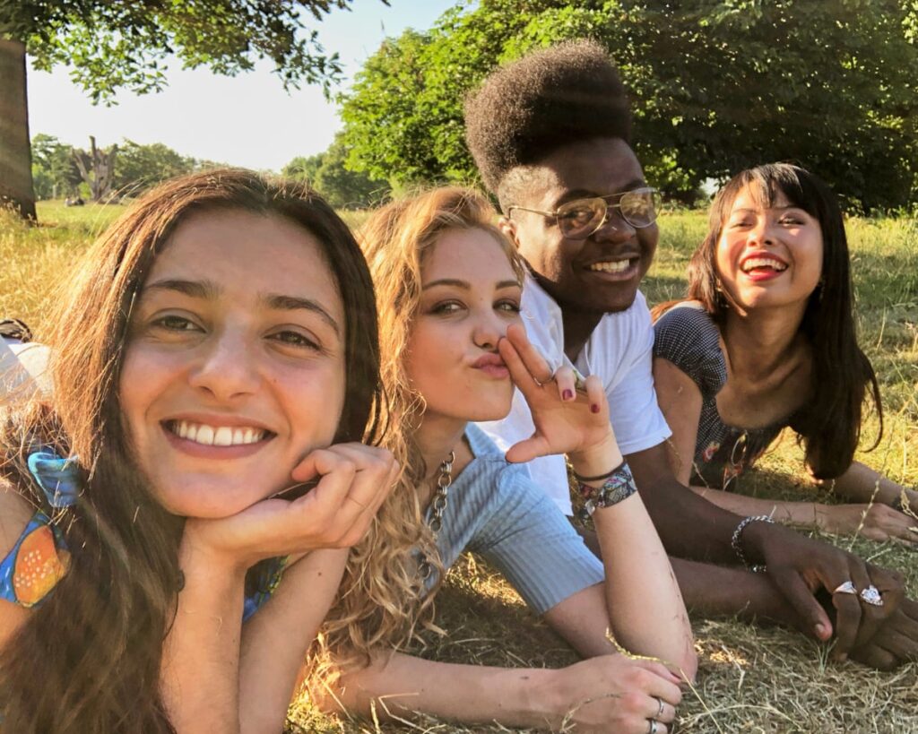 Group of teenagers boys and girls laying on their fronts on the grass